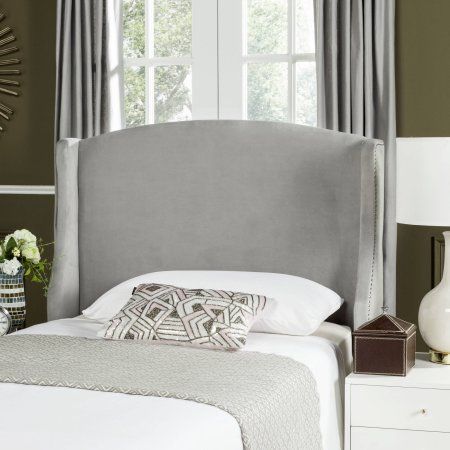 a bed with a gray headboard and pillows on top of it next to a window