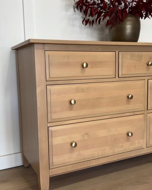 a wooden dresser with several drawers and a vase on top