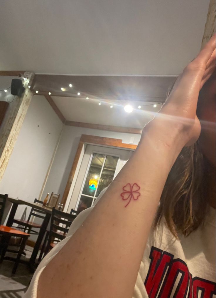 a woman with a small tattoo on her arm in a room filled with tables and chairs