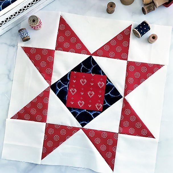 a red, white and blue quilt on a table next to some sewing supplies with scissors