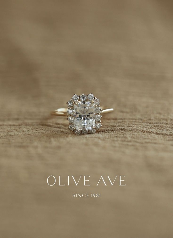 an oval cut diamond ring sitting on top of a piece of wood with the words olive ave above it