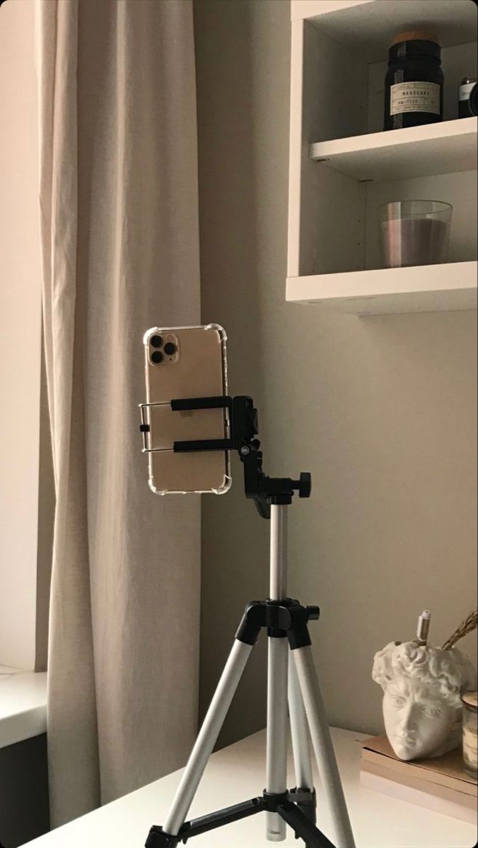 an iphone on a tripod in front of a window with the camera attached to it