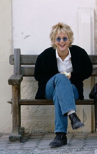 a woman is sitting on a wooden bench