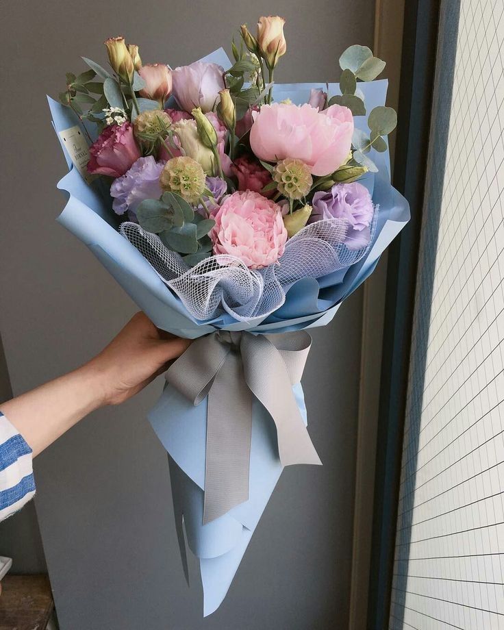 a person holding a bouquet of flowers in their left hand and wearing a blue shirt