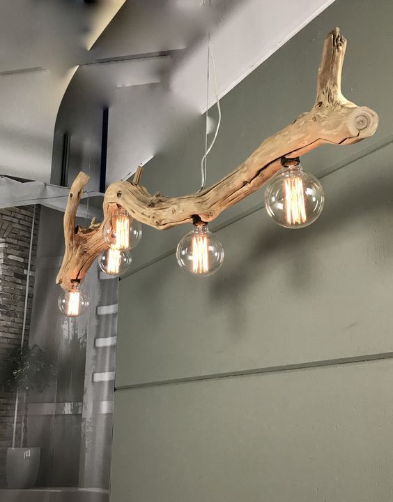 the light fixture is made from driftwood and has three bulbs on each side of it