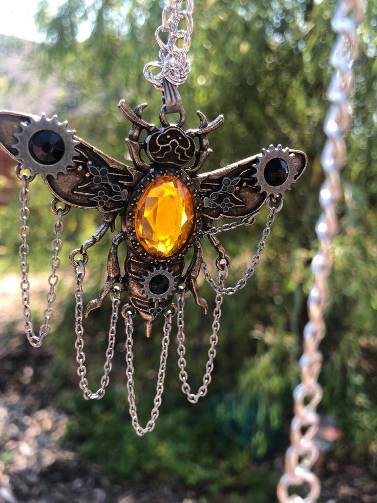 This steampunk bee necklace includes a 24" chain and an additional 3" for adjusting (can also be adjusted smaller than 24" due to chain type). The bee pendant is has an amber-yellow gem (3/4" x 1/2") and is 2 inches long and 2.5 inches from wingtip to wingtip. Chain is iron with a rhodium finish. Steampunk Gold Jewelry For Festivals, Unique Yellow Metal Jewelry, Gold Steampunk Jewelry For Festival, Steampunk Gold Jewelry For Halloween, Steampunk Style Chain Jewelry As Gift, Gold Steampunk Festival Jewelry, Steampunk Metal Necklaces For Festivals, Steampunk Metal Necklace For Festivals, Steampunk Bee