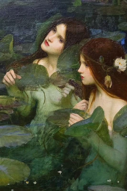 two women are in the water surrounded by lily pads and green leaves, one is looking at another woman's face