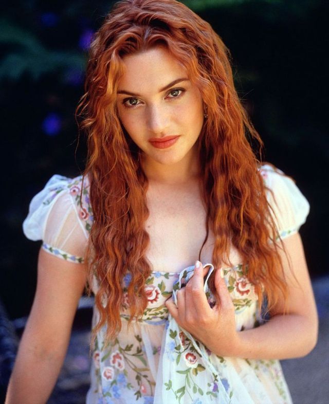 a woman with long red hair is posing for the camera and holding a cell phone