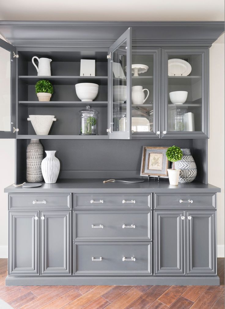 a gray china cabinet with white dishes and vases