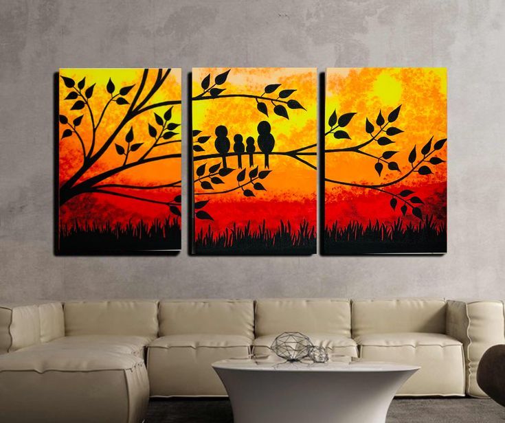 three birds sitting on a tree branch in front of an orange and yellow sunset painting