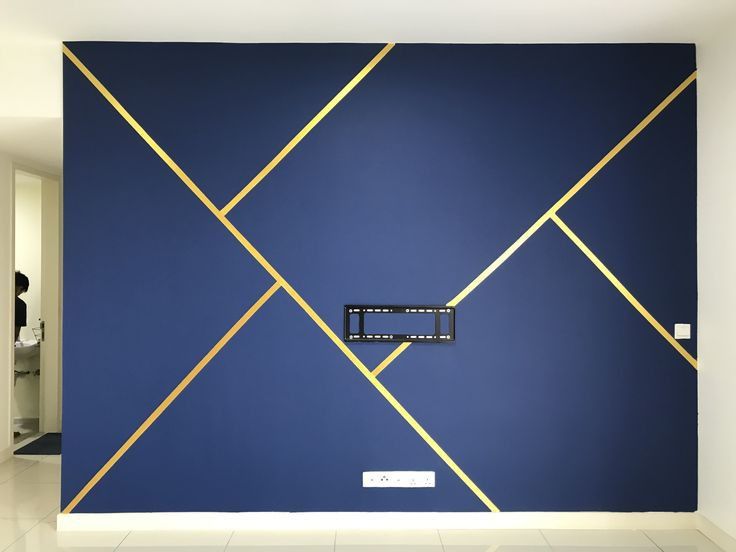 a blue wall with gold lines on it and a tv mounted to the wall in front of it