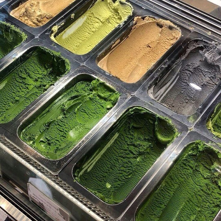 an assortment of ice creams in trays on display