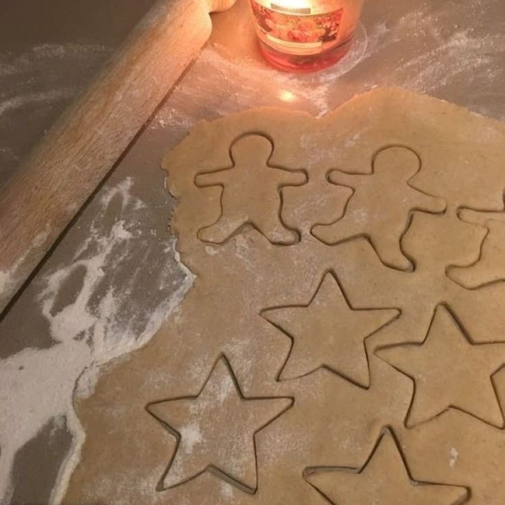 some cookies are sitting on a table next to a lit candle and cookie cutters