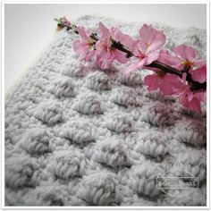 a crocheted blanket with pink flowers on it