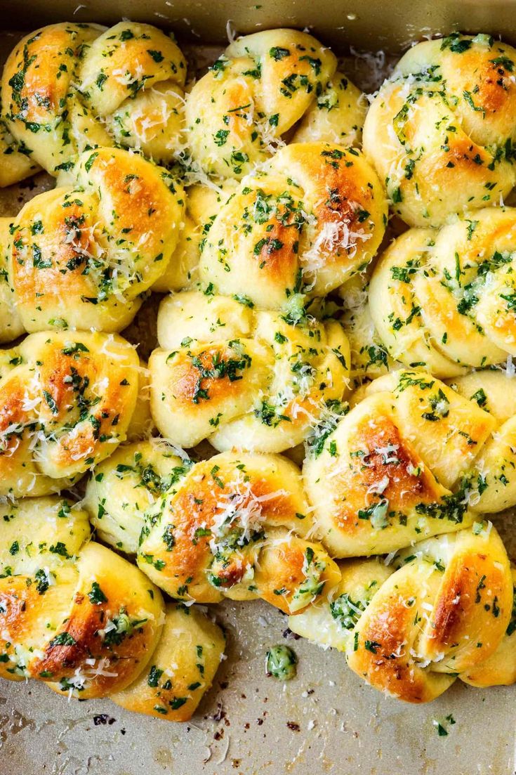 a baking pan filled with garlic bread rolls covered in cheese and parmesan sprinkles