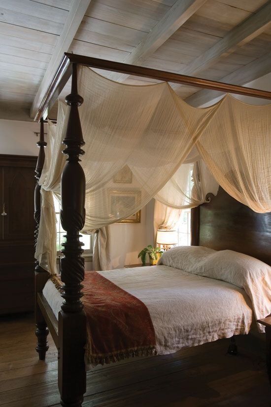 a canopy bed in a bedroom with wooden floors