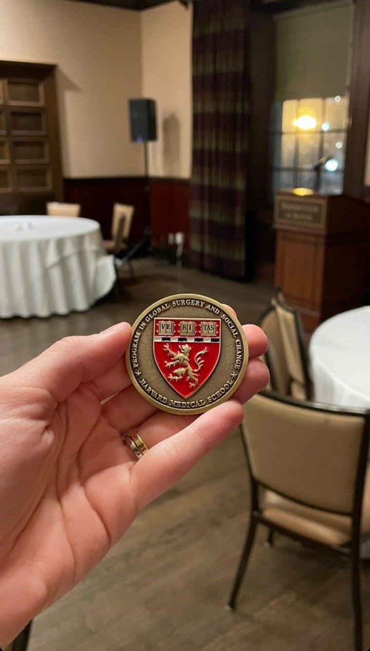 a person holding up a small badge in their hand at a banquet room with tables and chairs