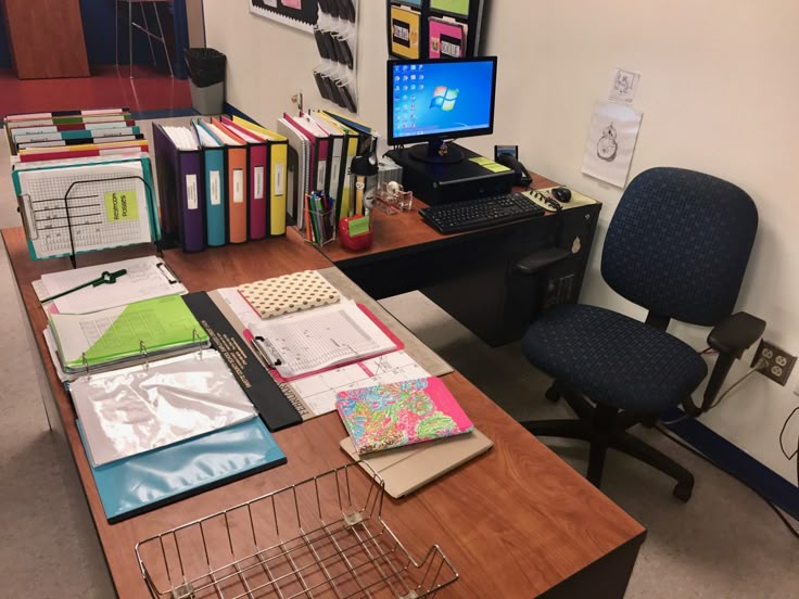 an office desk with several binders, books and computer equipment on top of it