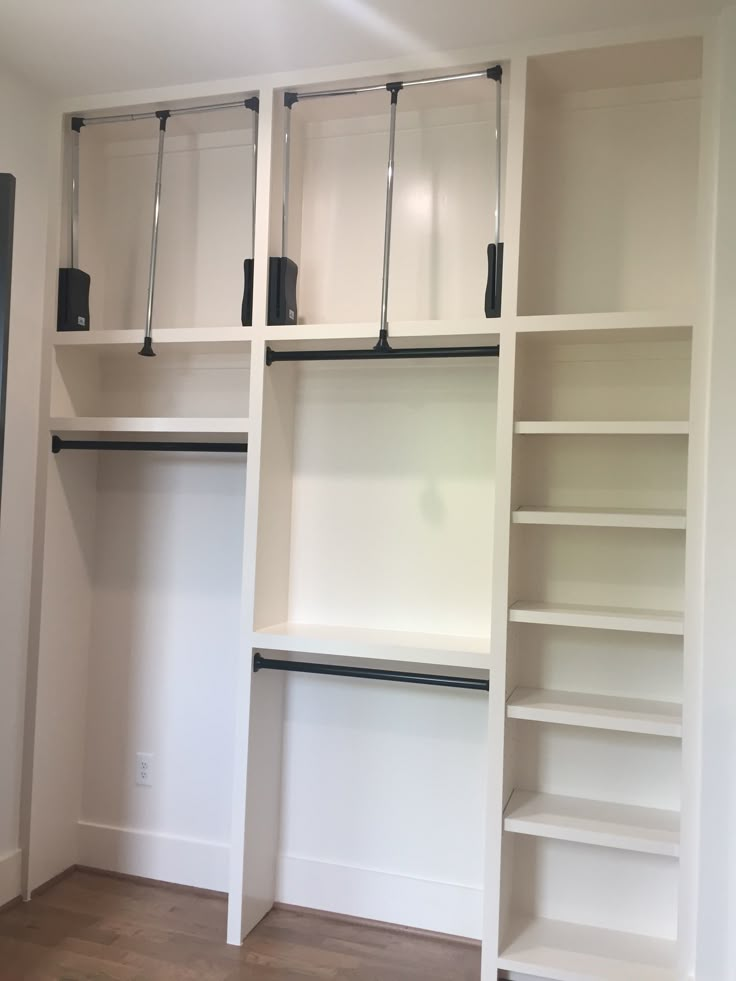 an empty room with white shelves and black handles on each shelf, along with wood flooring