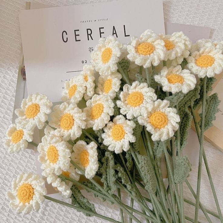 crocheted daisies are arranged next to a cerefal card on a table