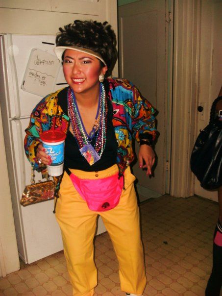 a woman in yellow pants and a colorful shirt holding a cup with her mouth open