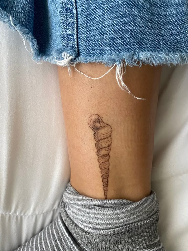 a woman's leg with a small tattoo of a cone on her left side