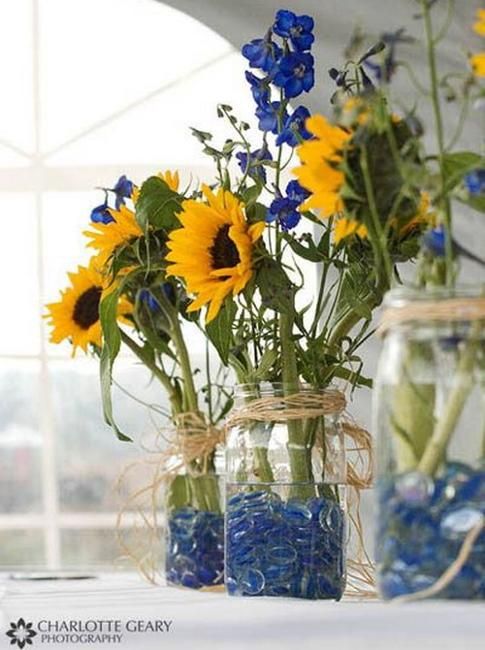 sunflowers and blue rocks are in glass jars