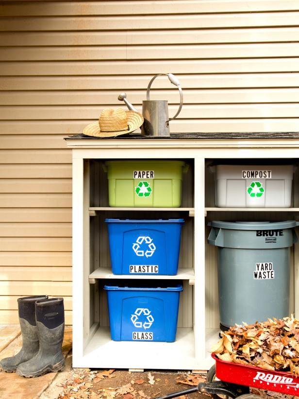 an outdoor storage unit with bins and trash cans