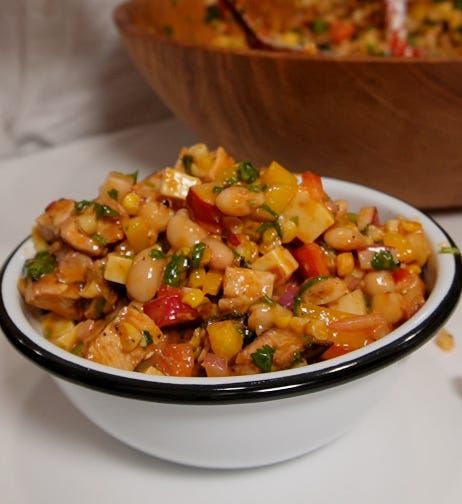 a white bowl filled with food on top of a table next to a wooden bowl