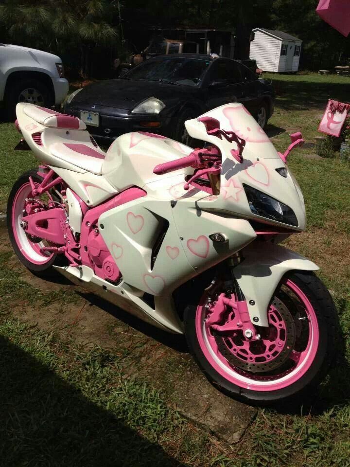 a pink and white motorcycle parked in the grass