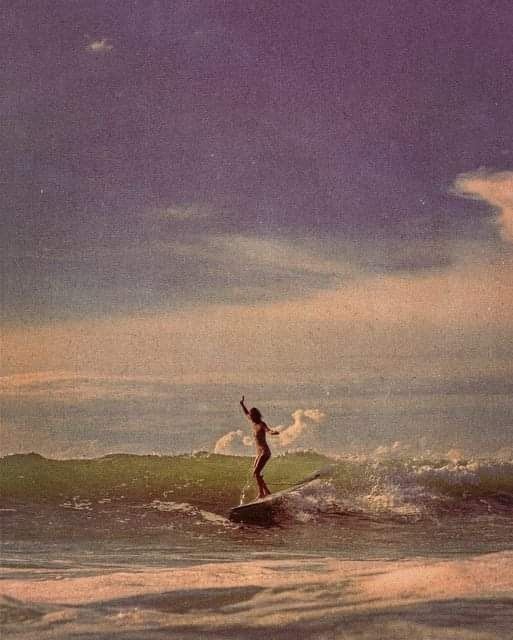 a person riding a surfboard on top of a wave in the ocean under a cloudy sky