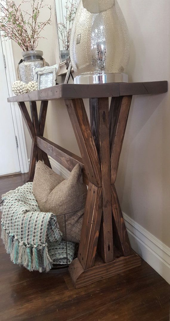 a wooden table sitting on top of a hard wood floor next to a vase filled with flowers