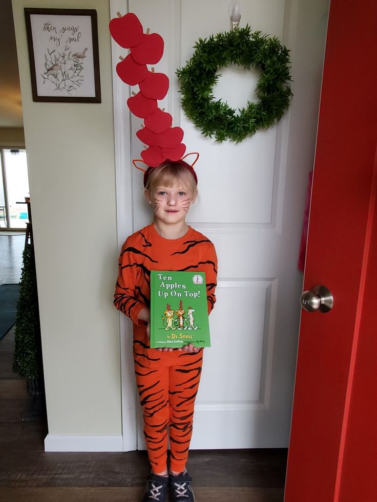 a little boy dressed up as a tiger holding a book in front of a door