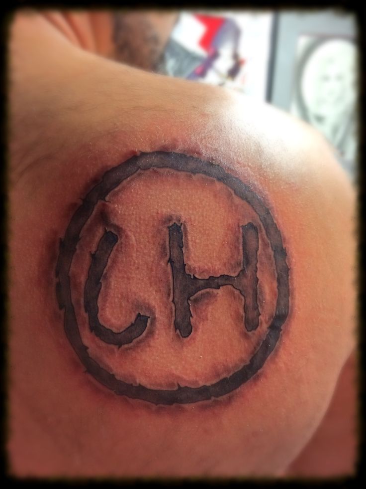 a man with a tattoo on his shoulder that has the letter h in it's center