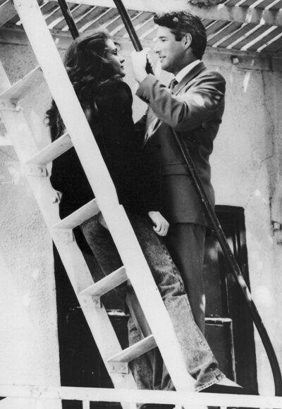 black and white photograph of two people standing on a ladder