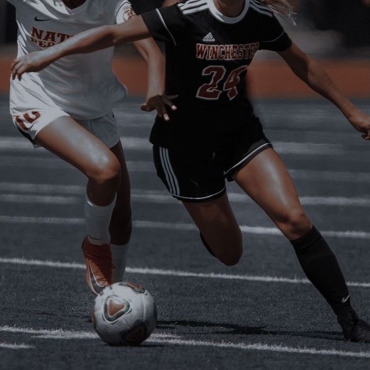 two girls are playing soccer on the field