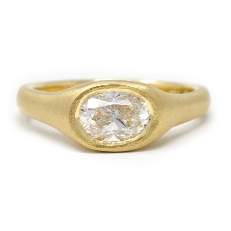 a yellow gold ring with an oval cut diamond in the center, on a white background