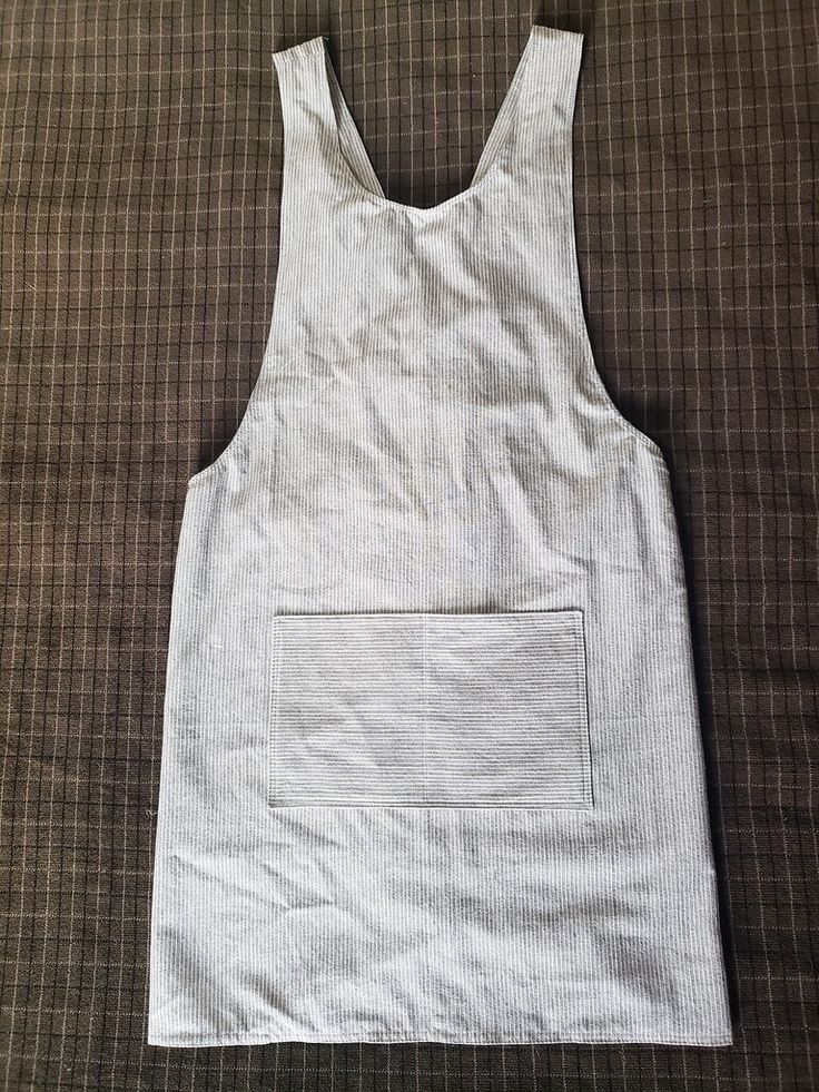 a white tank top with a pocket is laying on a brown cloth covered tablecloth