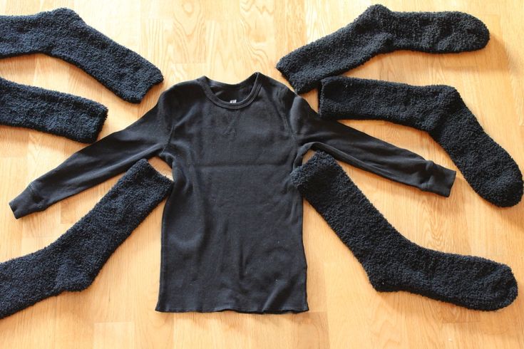 several pieces of black clothing laid out on a wooden floor, including gloves and leg warmers