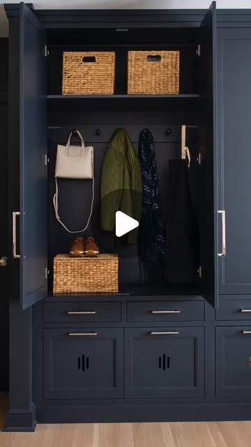 a large blue cabinet with baskets and clothes hanging on the door, in front of a wooden floor