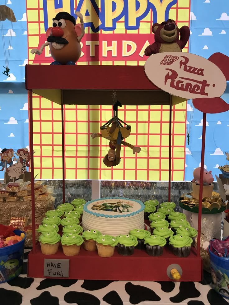 a birthday cake and cupcakes on display at a toy story themed birthday party