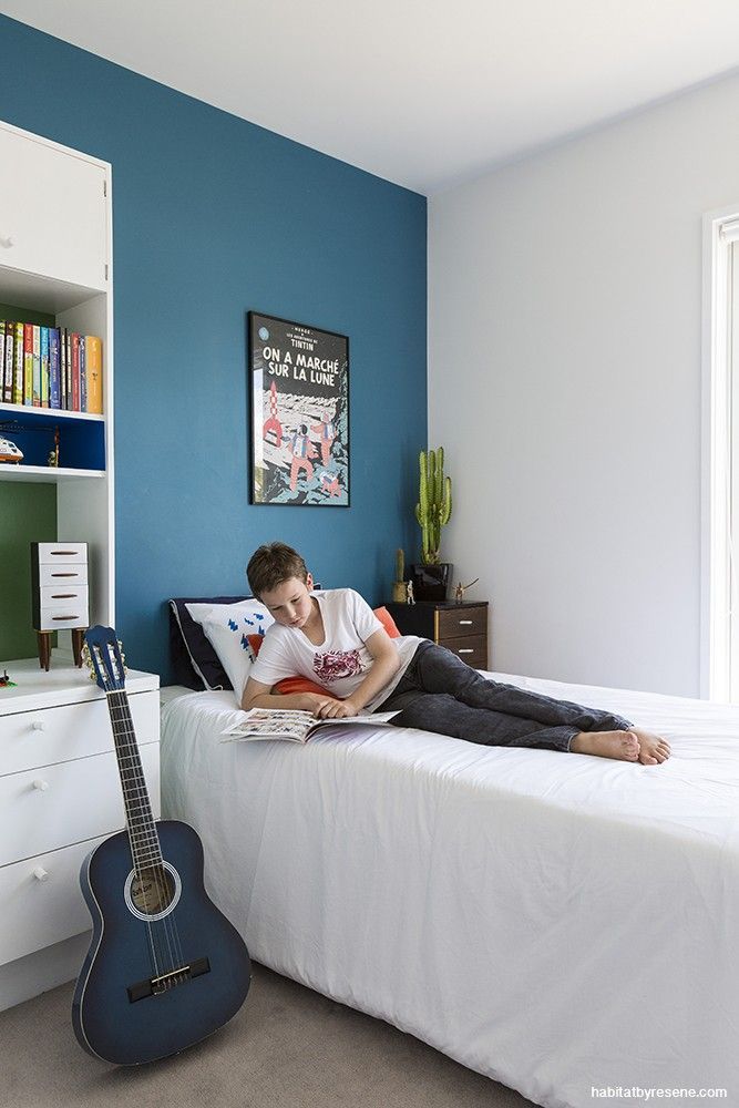 a person laying on a bed with a guitar in front of them and a blue wall