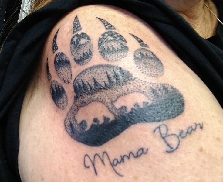 a woman with a tattoo on her arm that has a bear paw and the words mama bear written in black ink