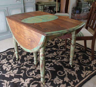 a wooden table sitting on top of a rug next to a chair and cupboards