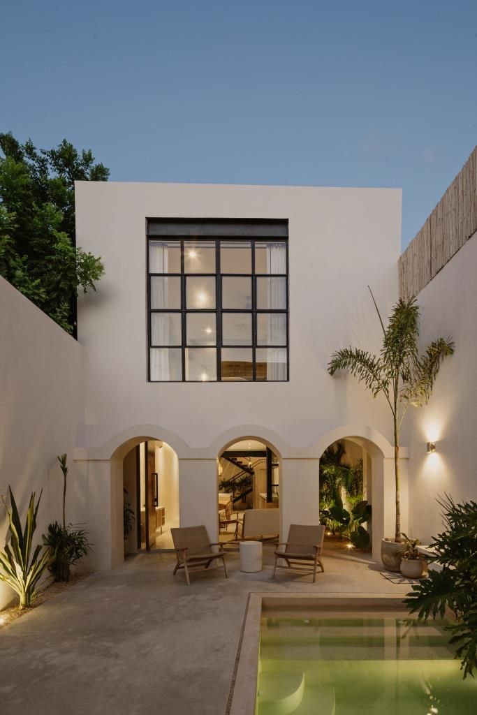 a house with a pool in front of it and lights on the side of the building