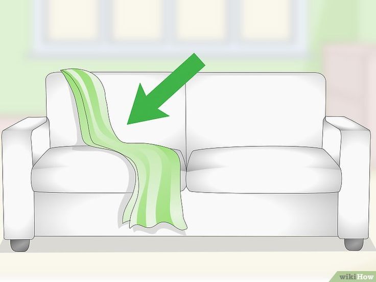 a white couch with a green blanket on it and an arrow pointing to the right