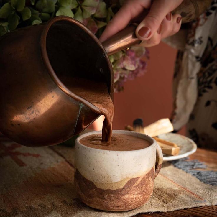 a person pouring chocolate into a cup on a table