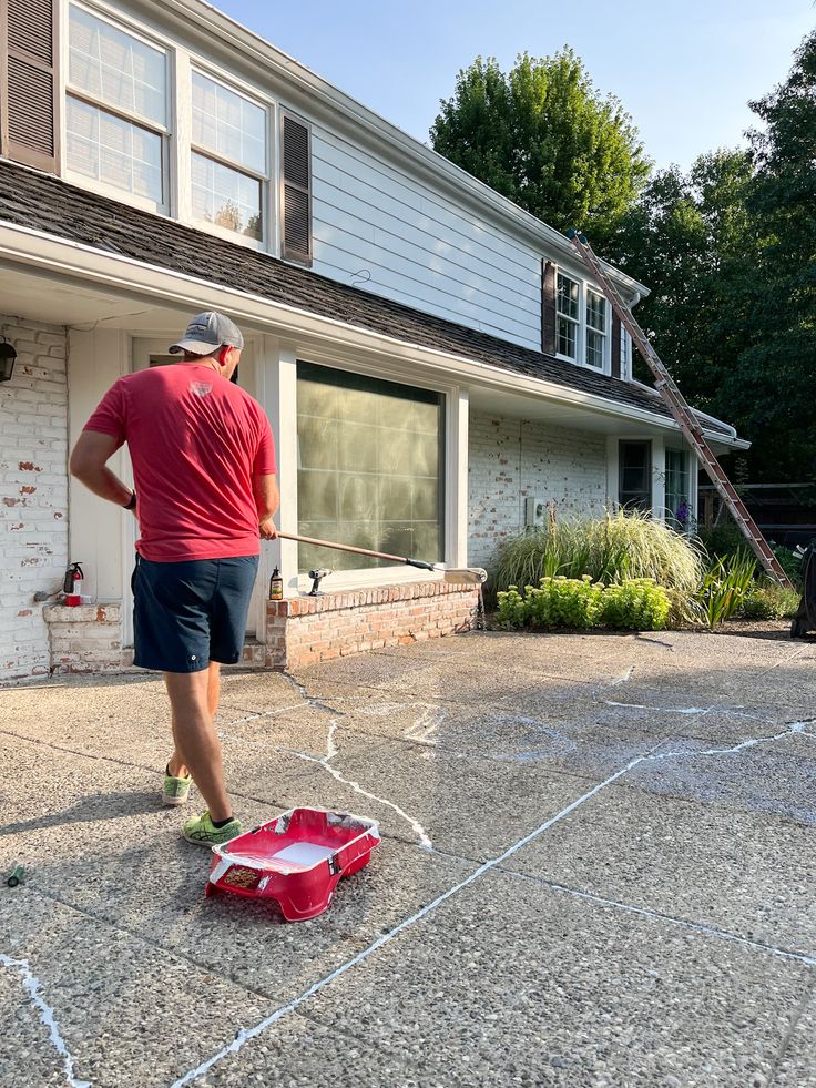 a man standing in front of a house with his back to the camera and looking at something on the ground