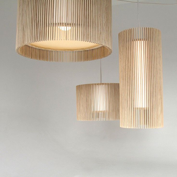 three wooden lamps hanging from the ceiling in a room with white walls and flooring