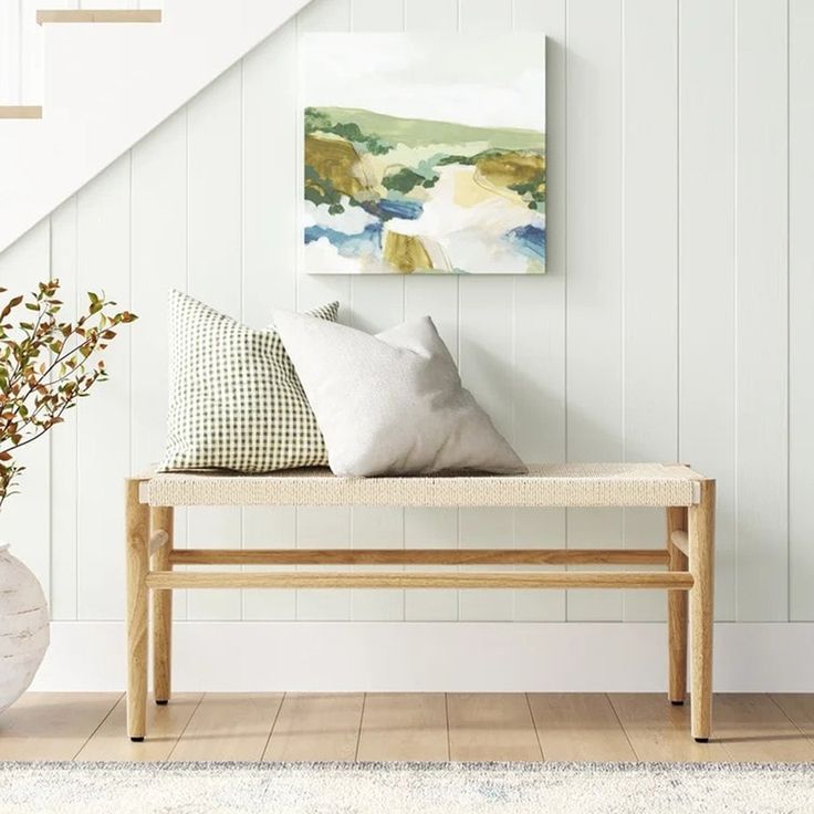 a wooden bench sitting under a stair case next to a vase with flowers on it